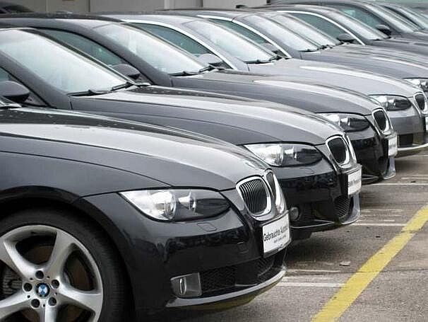 Mehrere dunkle Autos der selben Automarke parken nebeneinander auf einem Parkplatz eines Gebrauchtwagenhändlers.