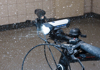 Ein Fahrrad steht in einem Labor im künstlichen Regen mit aktivierter Beleuchtung.
