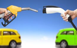 Ein gelber Treibstoff-Zapfhahn und ein weißes Ladekabel für ein Elektroauto zeigen zueinander, im Hintergrund sind ein gelbes und ein grünes Auto.
