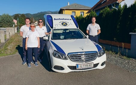 ÖAMTC-Clubmitglieder stehen gemeinsam mit Sanitätern vor einem Krankenfahrzeug.