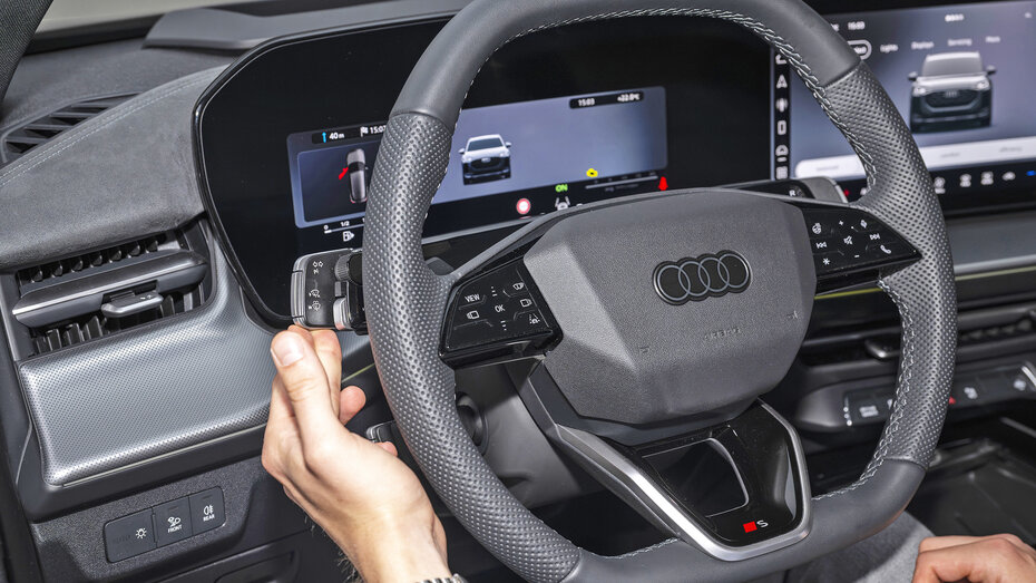 Eine Person berührt den Blinkerhebel eines Audis.