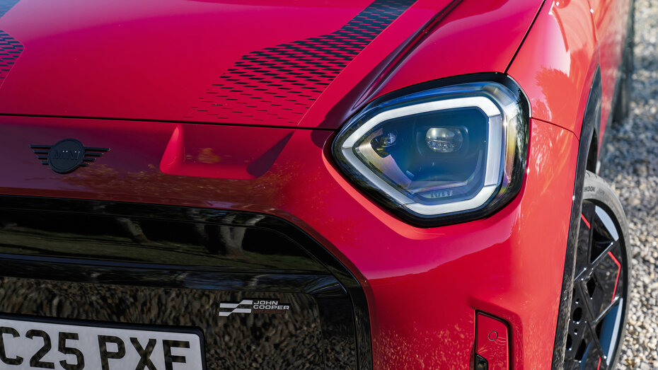 Scheinwerfer und schwarze Sportstreifen auf der Motorhaube eines roten Mini JCW Aceman