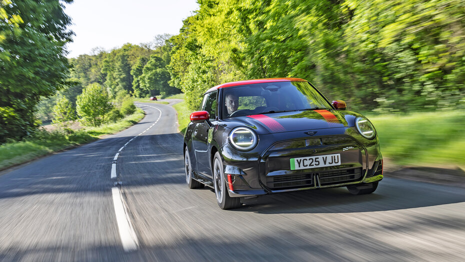 Ein schwarzer Mini JCW Electric fährt über eine Landstraße.