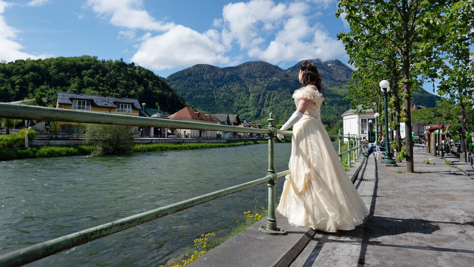 Frau im Sisi-Kostüm blickt auf den Fluss Traun.