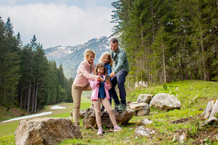 Eine Familie beim Wandern. Sie stehen auf einem felsigen Weg und betrachten das Handy, da es ein digitales Wandererlebnis ist.