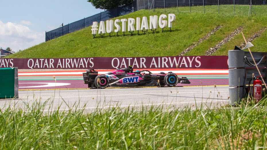 Ein Formel-1-Auto fährt auf der Rennstrecke an einem Austrian-GP-Schild vorbei.