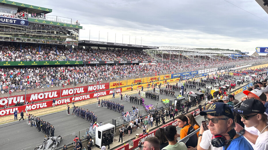 Kurz vorm Start in Le Mans, die Fahrer stehen in mehreren Reihen auf der Strecke.