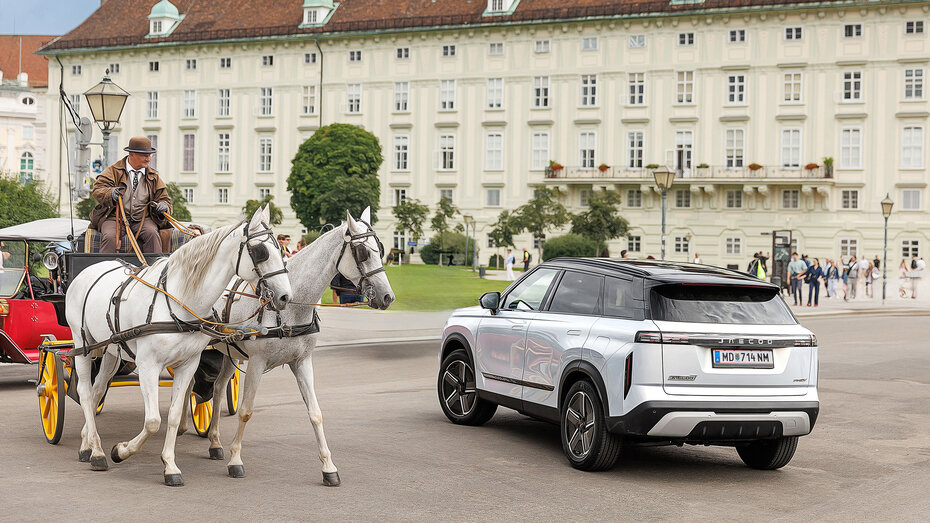 Ein weißes SUV fährt an einem Fiaker vorbei