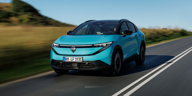 Ein türkiser Nissan Leaf von vorn auf einer Landstraße