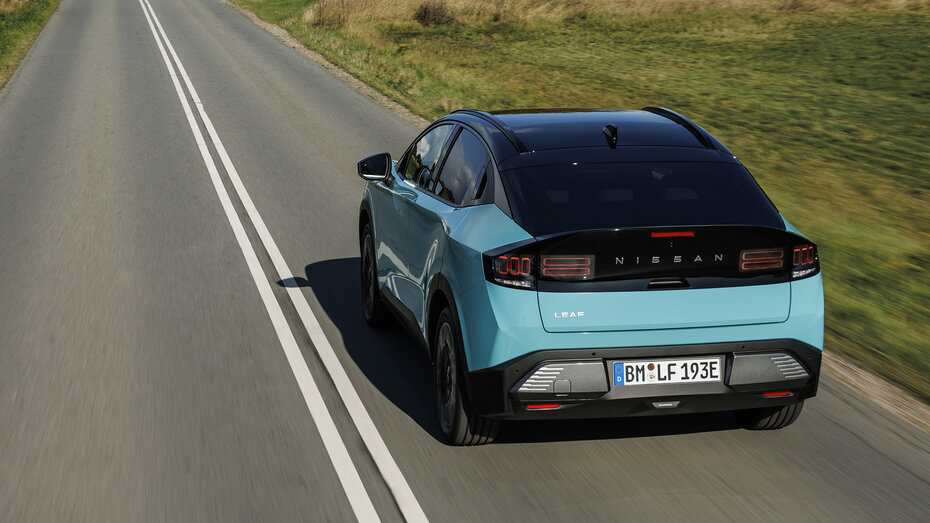 Ein türkiser Nissan Leaf von hinten auf einer Landstraße