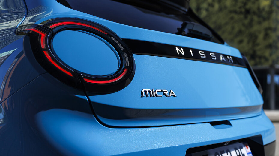 Die kreisförmige Heckleuchte sowie ein kleiner, chromfarbiger "Micra"-Schriftzug am Heck eines blauen Nissan Micra 2025.