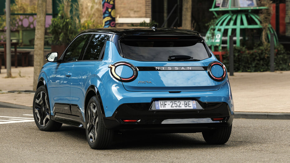 Heck eines blauen Nissan Micra, der vor einem Backsteingebäude steht.