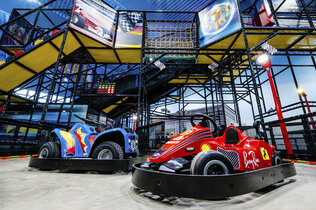 Rennautos und Klettergerüste im Hintergrund auf Indoor-Spielplatz.