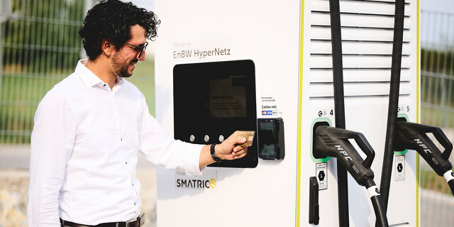 Ein Mann in weißem Hemd zahlt mit Kreditkarte an einer E-Ladesäule