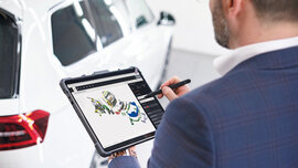 Michael Planer markiert auf einem Tablet beschädigte Teile eines Autos