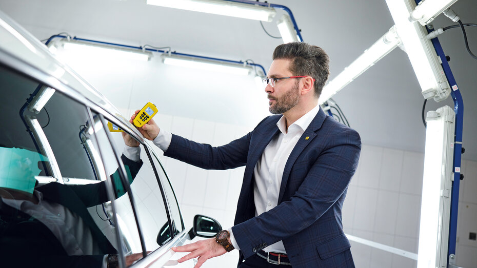 Michael Planer verwendet ein Lackschichtdichten-Messgerät an einem Auto