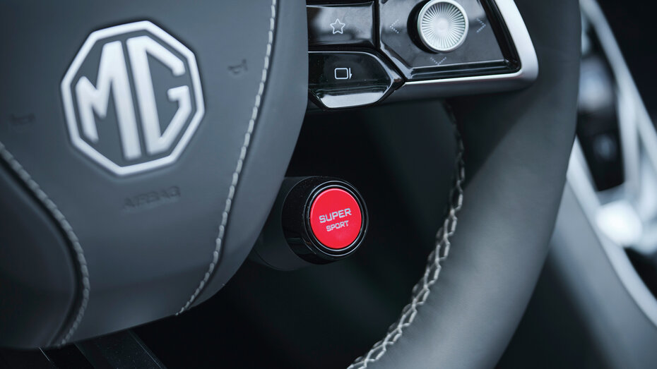 Rote Taste mit "Super-Sport"-Schriftzug am dunklen Leder-Lenkrad eines Fahrzeuge der Marke MG.