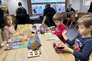 drei Kinder spielen auf einem Tisch im Café