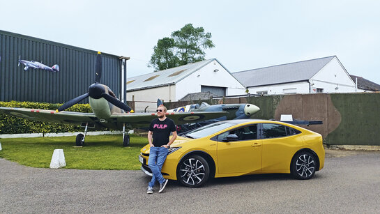 Toyota Prius in Südengland vor einem Spitfire-Flugzeug aus dem Zweiten Weltkrieg.