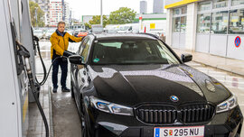 Ein Mann in gelber Jacke betankt ein schwarzes Auto