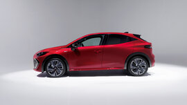 Ein roter Renault Clio in einem weißen Raum von der Seite