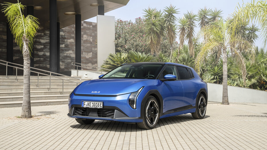 Ein blauer Kia EV4 steht vor einer modernen Villa zwischen Palmen.
