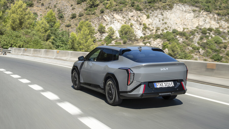 Ein graue Kia EV4-Limousine fährt über eine Landstraße.