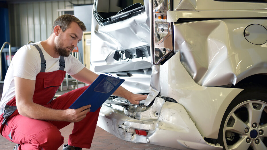 Mechaniker begutachtet Schaden am Heck eines Transporters