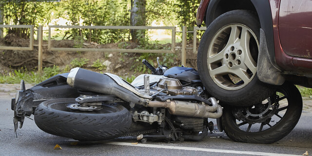 Ein Motorrad liegt unter dem Reifen eines Autos