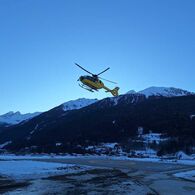 Ein gelber Notarzthubschrauber hebt in winterlicher Landschaft ab.