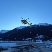 Ein gelber Notarzthubschrauber hebt in winterlicher Landschaft ab.
