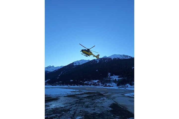 Ein gelber Notarzthubschrauber hebt in winterlicher Landschaft ab.