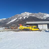Ein gelber Notarzthubschrauber in winterlicher Landschaft.