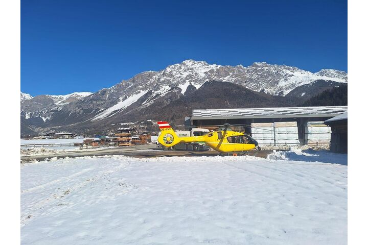 Ein gelber Notarzthubschrauber in winterlicher Landschaft.