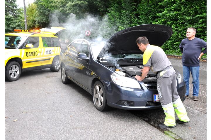 Pannenfahrer vor geöffneter Motorhaube, eine weitere Person steht daneben