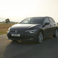 ÖAMTC-Studie: Reifenabrieb 2025 Auf dem Bild ist ein dunkles Auto zu sehen, das durch eine Landschaft fährt. Auf dem Kennzeichen des Autos steht "TEST".