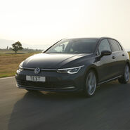 Auf dem Bild ist ein dunkles Auto zu sehen, das durch eine Landschaft fährt. Auf dem Kennzeichen des Autos steht "TEST".