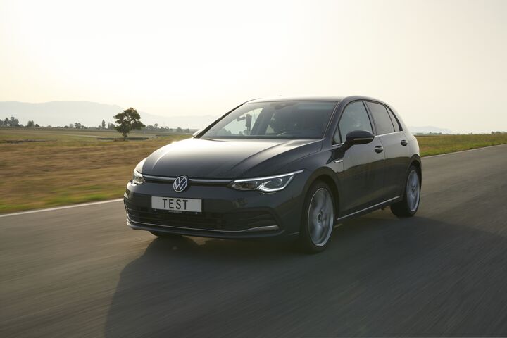 Auf dem Bild ist ein dunkles Auto zu sehen, das durch eine Landschaft fährt. Auf dem Kennzeichen des Autos steht "TEST".