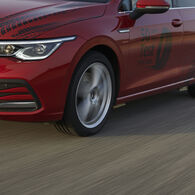 ÖAMTC-Studie: Reifenabrieb 2025 Auf dem Bild ist ein Teil eines roten Autos zu sehen, das durch eine Landschaft fährt. Auf der Tür des Autos steht in schwarzer Schrift "50 Jahre Reifen-Test".