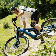 E-Mountainbiker mit Radhelm, der auf einem Berg abwärts fährt.