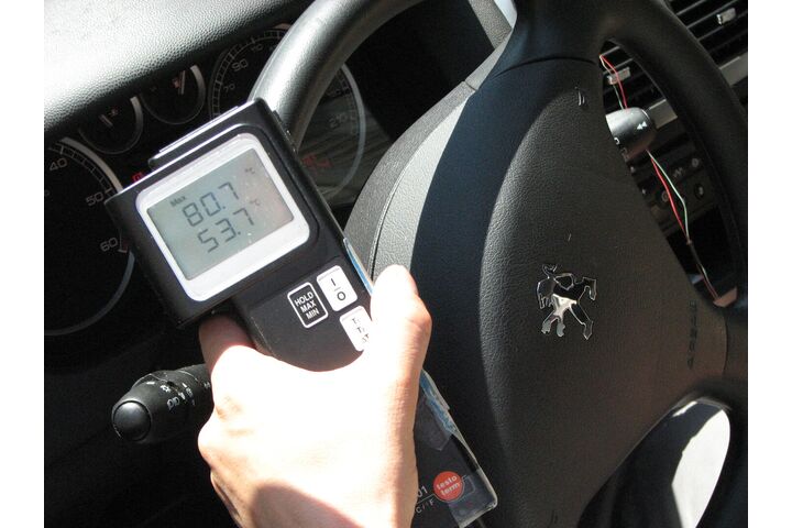 Man sieht ein Temperaturmessgerät, das über einem Auto-Lenkrad positioniert ist und 80 Grad Oberflächentemperatur anzeigt.