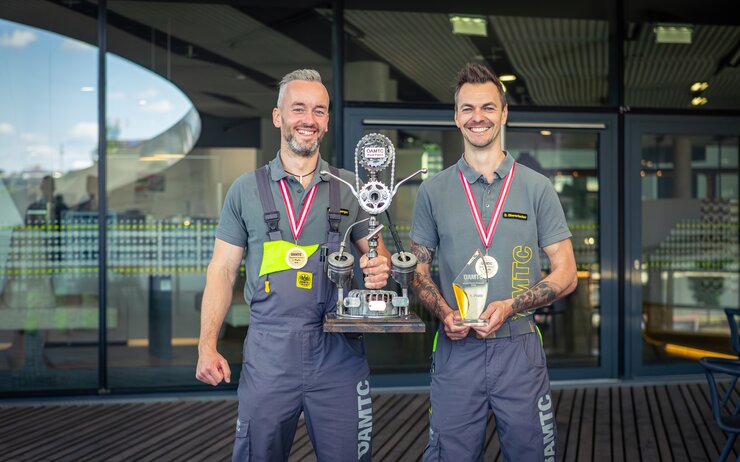 2 männliche Personen halten einen Siegerpokal
