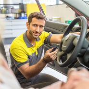 Ein grau-gelb gekleiderter ÖAMTC-Techniker in der offenen Tür eines Fahrzeugs