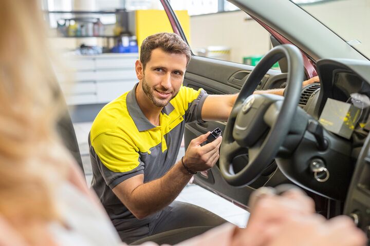 Ein grau-gelb gekleiderter ÖAMTC-Techniker in der offenen Tür eines Fahrzeugs