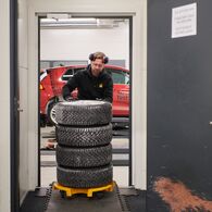 ÖAMTC_Winterreifentest-1 Ein Techniker verstaut gestapelte Winterreifen nach einem Test auf Schneefahrbahn.