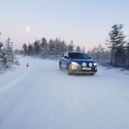 Ein Testfahrzeug testet die Reifen auf winterlicher Fahrbahn in einer nordischen Kulisse mit einem aufgehenden Mond