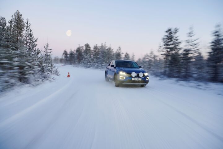 Ein Testfahrzeug testet die Reifen auf winterlicher Fahrbahn in einer nordischen Kulisse mit einem aufgehenden Mond