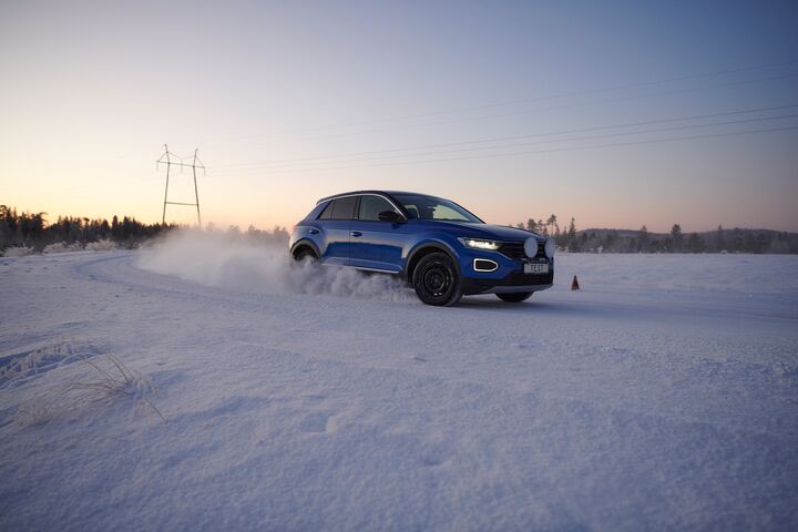 Ein Testfahrzeug driftet mit Winterreifen auf winterlicher Fahrbahn während die Sonne untergeht 