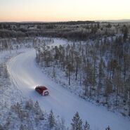 Ein Testfahrzeug fährt durch eine winterliche Forststraße