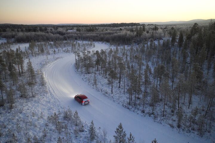Ein Testfahrzeug fährt durch eine winterliche Forststraße
